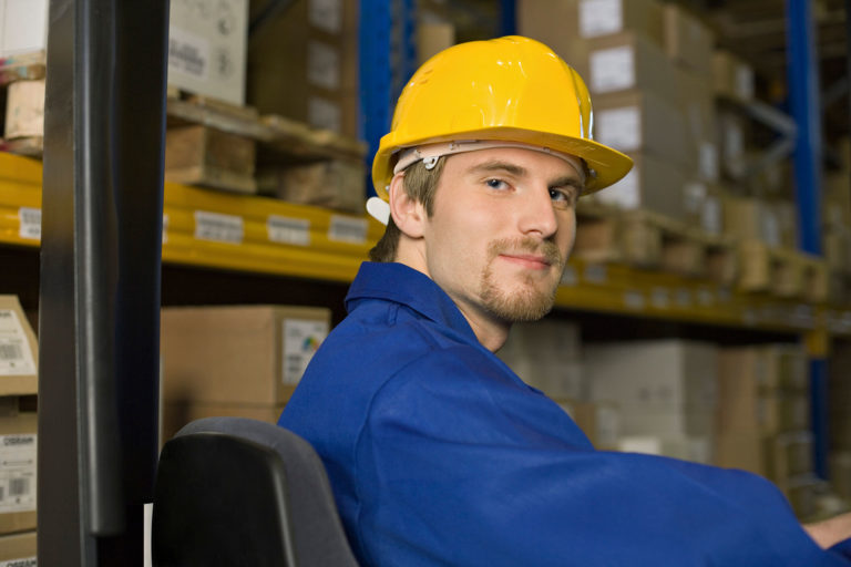 A warehouse worker looking at the camera while at word
